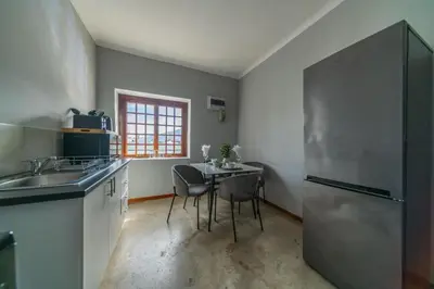 a kitchen with a table and a stainless steel refrigerator at Huguenot Franschhoek in Franschhoek