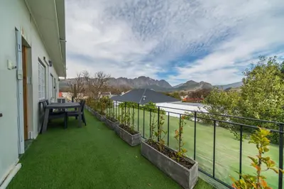 a balcony with green grass and a table on it at Huguenot Franschhoek in Franschhoek