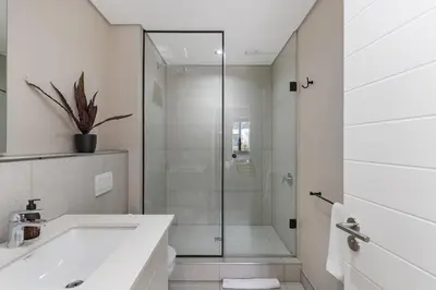 a white bathroom with a shower and a sink at Bridgewater One 309 in Cape Town