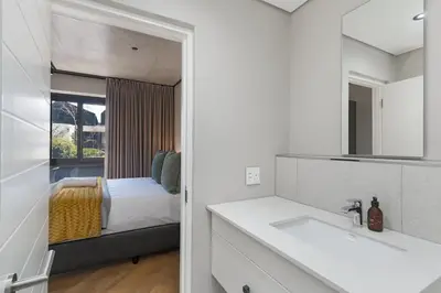 a bathroom with a sink and a bedroom with a bed at Bridgewater One 309 in Cape Town
