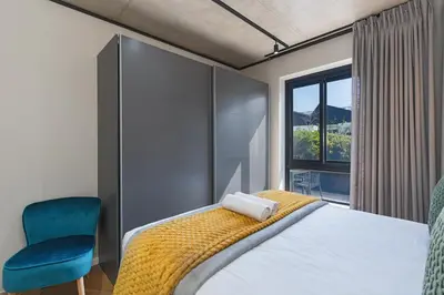a bedroom with a bed and a chair and a window at Bridgewater One 309 in Cape Town