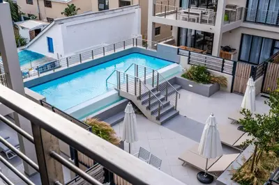 an overhead view of a swimming pool on a building with umbrellas at Esplanade Hermanus Central Sea Views in Hermanus