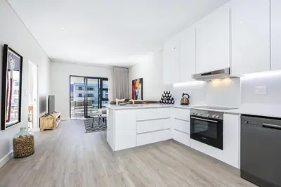 a large white kitchen with white cabinets and appliances at Esplanade Hermanus Central Sea Views in Hermanus