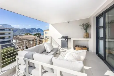 a living room with white furniture and a balcony at Esplanade Hermanus Central Sea Views in Hermanus