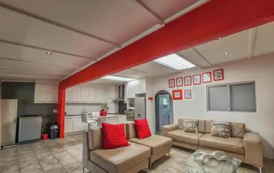 a living room with two couches and a kitchen at Sealax Cottage Fleurpark in Gordonʼs Bay