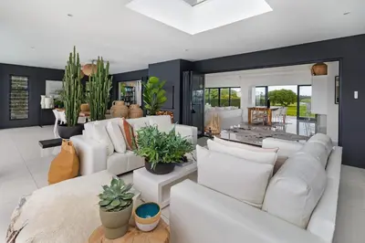 a living room with white furniture and plants at Sunset Fairway Vista Villa in Cape Town