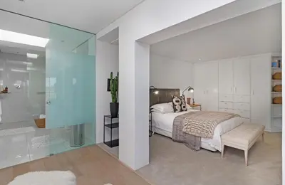 a bedroom with a bed and a glass wall at Sunset Fairway Vista Villa in Cape Town