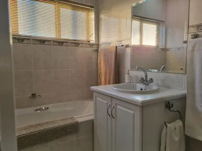 a bathroom with a sink and a bath tub and a tubermottermott at Flat 9, Beachfront 2 Bedroom with Sea View for 4 in Gordonʼs Bay