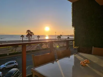 a sunset from a balcony with a view of the beach at Flat 9, Beachfront 2 Bedroom with Sea View for 4 in Gordonʼs Bay