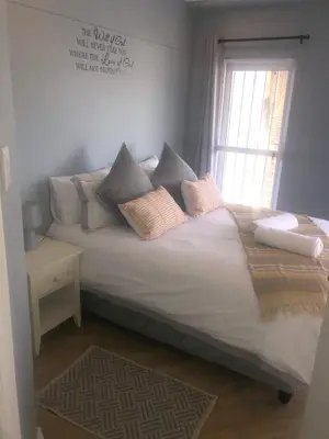 a bedroom with a bed with pillows and a window at Palmsbeach 5 in Strand