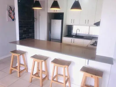 a kitchen with a counter and stools in it at Palmsbeach 5 in Strand