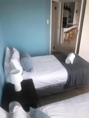 a bedroom with two beds and a table with a mirror at Palmsbeach 5 in Strand