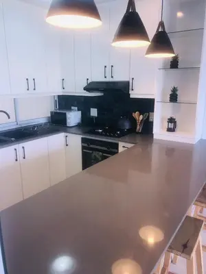 a kitchen with white cabinets and a large counter top at Palmsbeach 5 in Strand