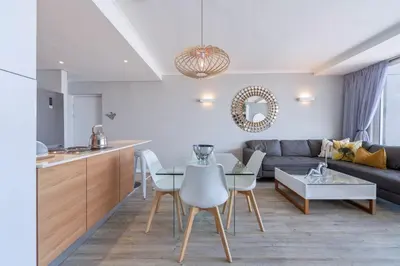a kitchen and living room with a couch and a table at Horizon Bay 903 Fresh Beachfront Hideaway in Cape Town