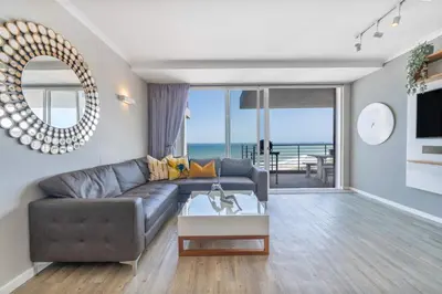 a living room with a couch and a table at Horizon Bay 903 Fresh Beachfront Hideaway in Cape Town