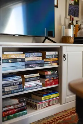 a pile of books sitting on a shelf under a tv at The Pearl in the Winelands in Paarl