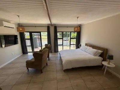 a bedroom with a bed and a chair and windows at Worcester accommodation Putt and Stay in Worcester