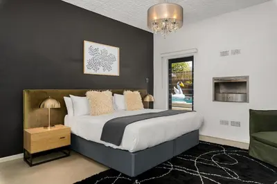 a bedroom with a large bed and a chandelier at Luxury Family Villa with Pool, Gym & Bonfire Area in Cape Town