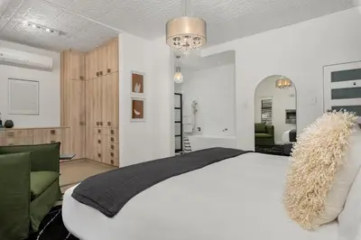 a bedroom with a large white bed and a bathroom at Luxury Family Villa with Pool, Gym & Bonfire Area in Cape Town