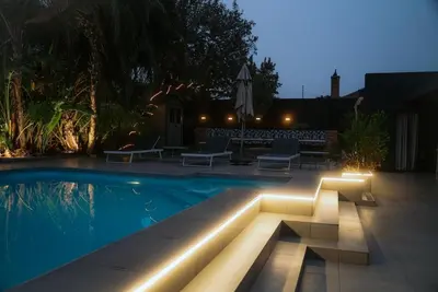 a swimming pool with lights in a backyard at night at Luxury Family Villa with Pool, Gym & Bonfire Area in Cape Town