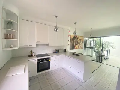 a kitchen with white cabinets and a large window at Ocean & Mountain View Apartment in Gordonʼs Bay