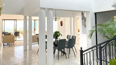 a dining room and living room with a table and chairs at Ocean & Mountain View Apartment in Gordonʼs Bay