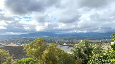 a view of a city under a cloudy sky at Ocean & Mountain View Apartment in Gordonʼs Bay