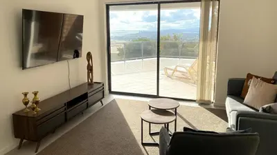 a living room with a couch and a large window at Ocean & Mountain View Apartment in Gordonʼs Bay