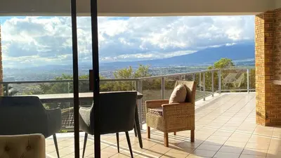 a balcony with chairs and a view of the mountains at Ocean & Mountain View Apartment in Gordonʼs Bay