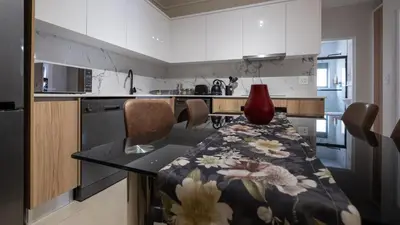 a kitchen with a table with a red vase on it at AlimamaSpaces The Fynbos Chelsea in Cape Town