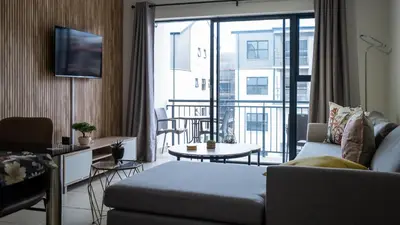 a living room with a couch and a balcony at AlimamaSpaces The Fynbos Chelsea in Cape Town
