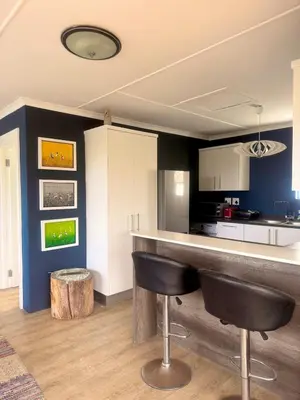 a kitchen with a bar with black chairs in it at Loft Escape in Onrus with Hot Tub- 2km from beach in Hermanus