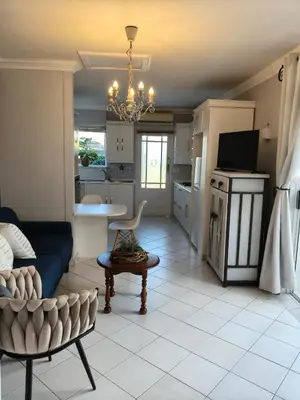 a living room with a blue couch and a kitchen at Strand and Sea Cottage in Strand