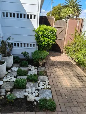 a garden with a brick walkway next to a house at Strand and Sea Cottage in Strand