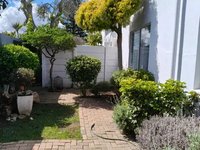 a garden in front of a white house at Strand and Sea Cottage in Strand