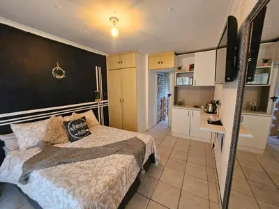 a bedroom with a bed and a small kitchen at 12 on lake Grassy Park in Parkwood