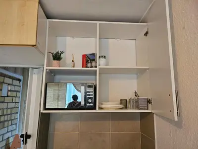 a kitchen with white cabinets and a microwave at 12 on lake Grassy Park in Parkwood