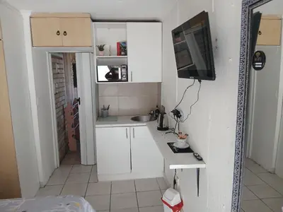 a small kitchen with white cabinets and a flat screen tv at 12 on lake Grassy Park in Parkwood