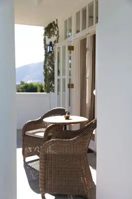 a patio with a table and chairs on a porch at Lily Pond House at Le Lude in Franschhoek