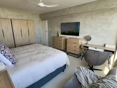 a bedroom with a bed and a desk and a chair at Casa Praia in Strand