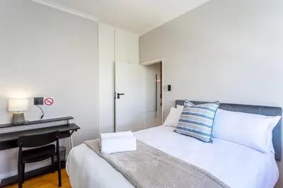 a bedroom with a bed with a desk and a bed sidx sidx sidx at Burmeister Circle by CTHA in Cape Town