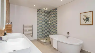 a white bathroom with a tub and a sink at Le Paradis 5 in Hermanus