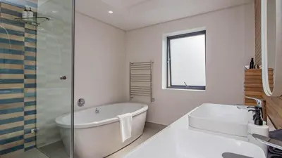 a white bathroom with a tub and a sink at Le Paradis 5 in Hermanus
