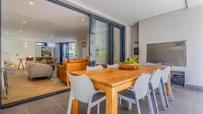 a dining room with a wooden table and white chairs at Le Paradis 5 in Hermanus
