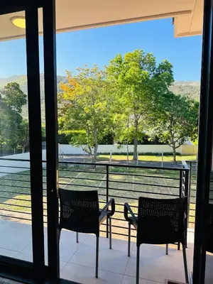 two chairs on a balcony with a view of a field at Two Horizons Apartment 6 in Hermanus