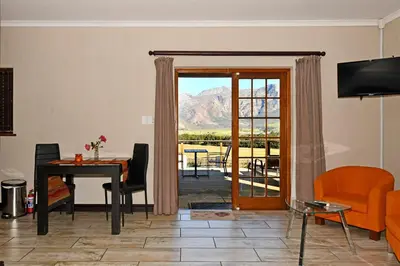 a living room with a door open to a patio at Topiary Wine Estate & Cottages in Franschhoek