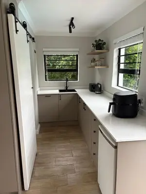 a kitchen with white counters and a sink and a window at Suburban Bliss in Stellenbosch