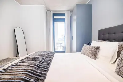 a bedroom with a large white bed and a window at Riverlands - Lux 1 bedroom Apartment with Parking in Cape Town