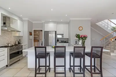 a kitchen with a large white island with bar chairs at Ocean Whisper Terrace Villa in Cape Town
