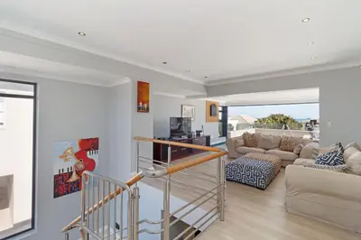 a living room with a staircase and a couch at Ocean Whisper Terrace Villa in Cape Town